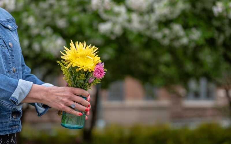 vrouw op straat met vaas met bloemen in handen
